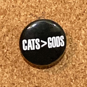 Puede incluir: Un botón negro con texto blanco que dice "CATS>GODS".