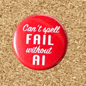 May include: A round, red button with white text. The text reads "Can't spell FAIL without AI". The button is set against a textured, tan background.
