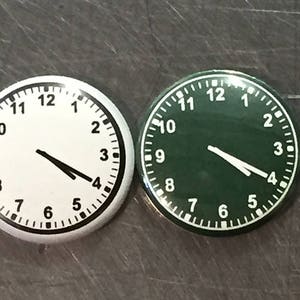 May include: Two round clocks, one with a white face and black hands and the other with a green face and white hands. Both clocks have black numbers.