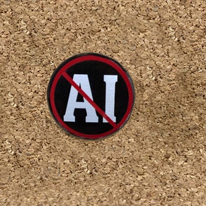 Puede incluir: Un bot&oacute;n negro y rojo con una l&iacute;nea diagonal blanca que atraviesa las letras "AI".