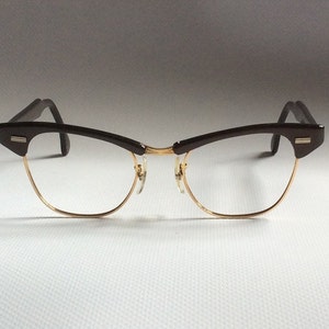 May include: Brown and gold cat-eye glasses with a thin metal frame.