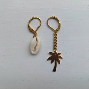 May include: A pair of gold earrings with a white seashell charm and a gold palm tree charm.