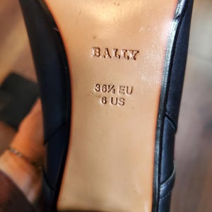 May include: Close-up of the sole of a black leather shoe. The brand name "BALLY" is embossed on the tan insole. The shoe size is indicated as 36 1/2 EU and 6 US.