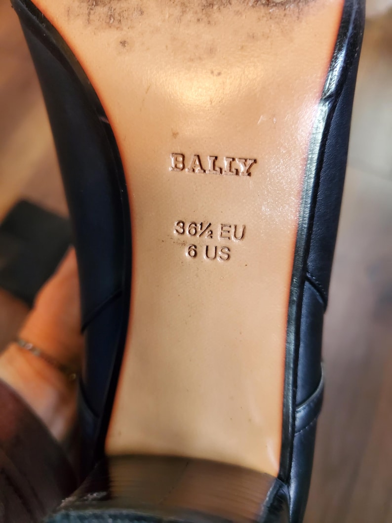May include: Close-up of the sole of a black leather shoe. The brand name "BALLY" is embossed on the tan insole. The shoe size is indicated as 36 1/2 EU and 6 US.