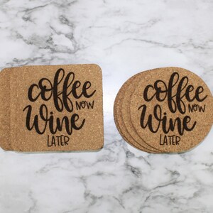 May include: Two cork coasters with the text "coffee now wine later" in black script. One coaster is square and the other is round.