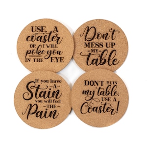 May include: Set of four cork coasters with funny sayings about using coasters. The coasters feature the text: "Use a coaster or I will poke you in the eye", "Don't mess up my table", "If you leave a stain you will feel the pain", and "Don't ruin my table. Use a coaster!"