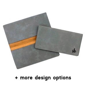 May include: A gray leather wallet with a brown interior and a smaller gray wallet with the initials "sb" embossed on the front.