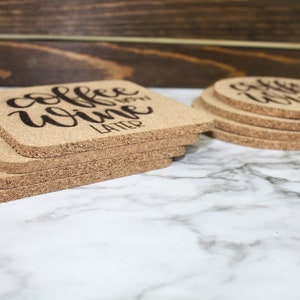 May include: A set of six cork coasters with the text "coffee wine later" printed in black on a natural cork surface.