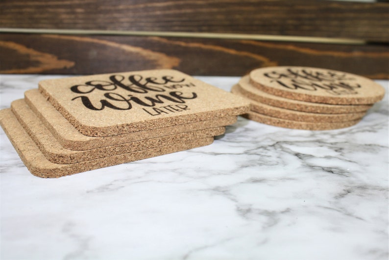 May include: A set of six cork coasters with the text "coffee wine later" printed in black on a natural cork surface.