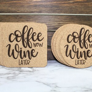 May include: Set of six round cork coasters with the text "coffee now wine later" in black script font. The coasters are stacked on a white marble surface.