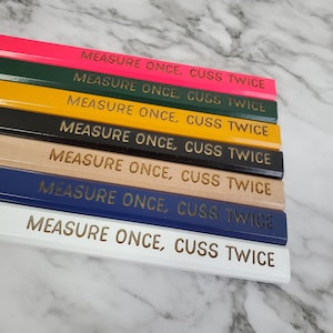May include: A set of eight pencils with different colored bodies and white lettering. The pencils have the phrase "Measure Once, Cuss Twice" printed on them.