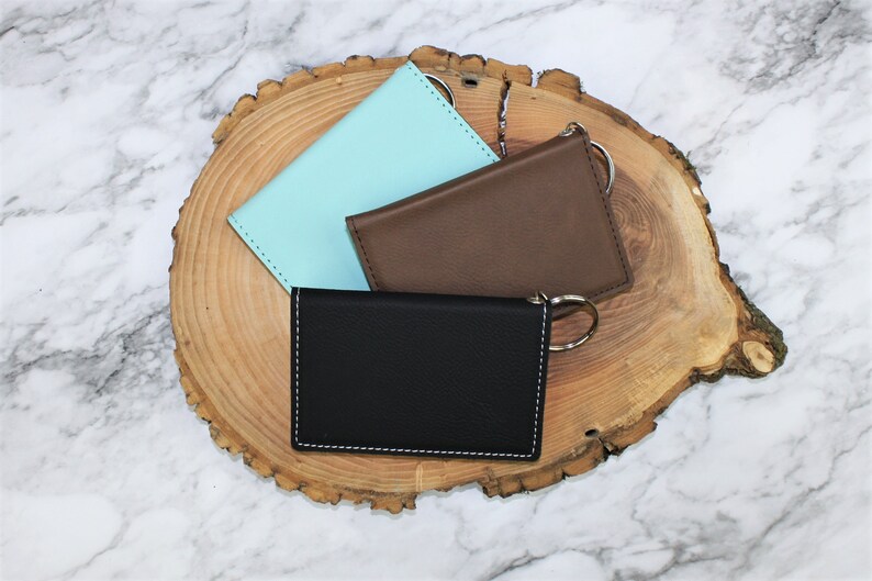 May include: Three leather card holders with key rings. The card holders are in black, brown, and light blue.