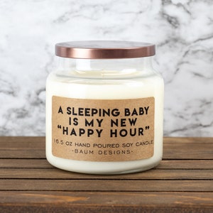 K&ouml;nnte beinhalten: Eine Glas-Kerze in einem Glas mit einem Kupferdeckel und einem braunen Papieretikett mit der Aufschrift "A sleeping baby is my new "happy hour"" 16.5 oz hand poured soy candle - Baum Designs -