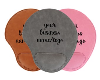 May include: Three mousepads in different colors: brown, gray, and pink. Each mousepad has a raised wrist rest and a smooth surface. The gray mousepad has the text "your business name/logo" printed on it.