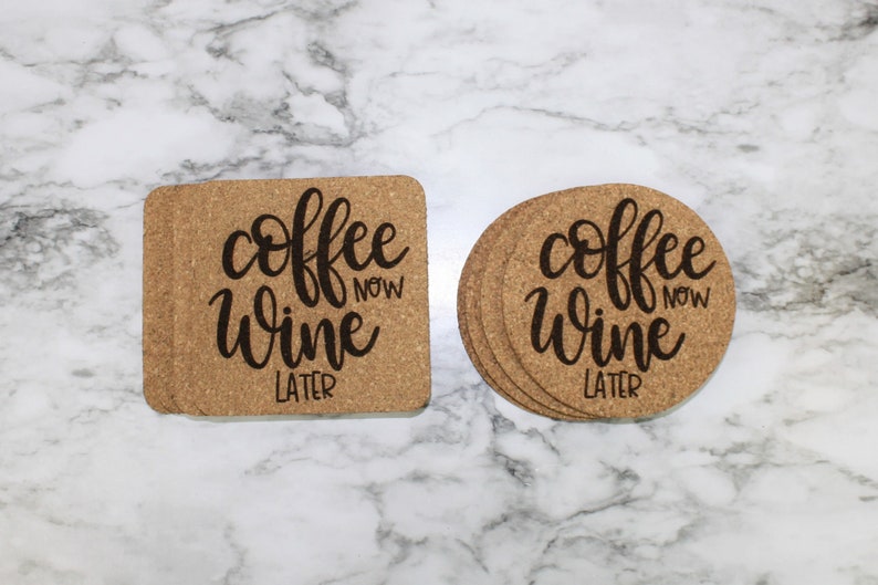 May include: Two cork coasters with the text "coffee now wine later" in black script. One coaster is square and the other is round.