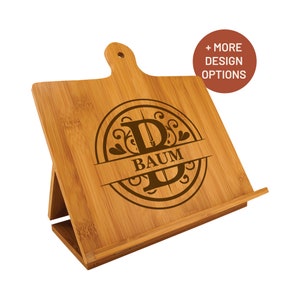 May include: A bamboo cookbook stand with a cutting board top. The stand is engraved with a monogram design featuring the letter "B" and the name "BAUM".