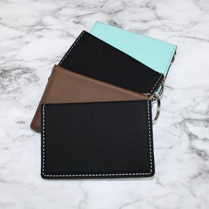 May include: Three leather keychains in black, brown, and light blue. Each keychain has a silver ring.