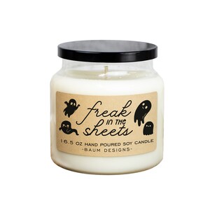 May include: A white soy candle in a glass jar with a black lid. The label features the text "freak in the sheets" with ghost illustrations. The candle weighs 16.5 oz and is hand-poured.