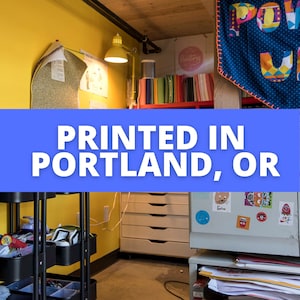 K&ouml;nnte beinhalten: Ein kleiner Arbeitsbereich mit gelben W&auml;nden, einem schwarzen Rollwagen, einem wei&szlig;en Aktenschrank und einem wei&szlig;en K&uuml;hlschrank mit Magneten. Der Text "PRINTED IN PORTLAND, OR" ist auf einem blauen Banner zu sehen.