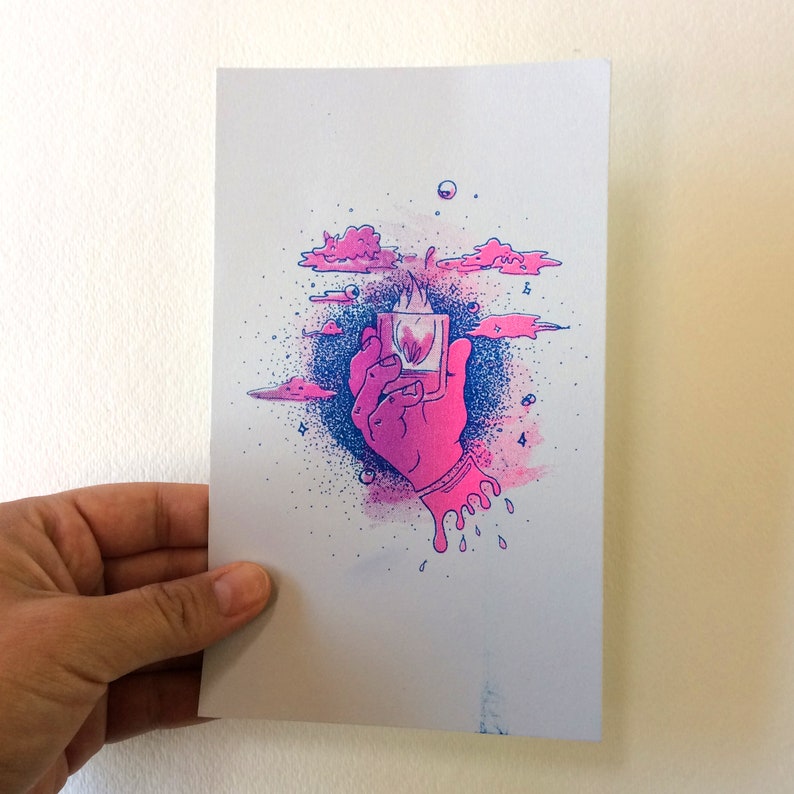 May include: A pink and blue illustration of a hand holding a square object with a flame inside. Pink clouds and blue splatter surround the hand. The artwork has a surreal, dreamlike quality.