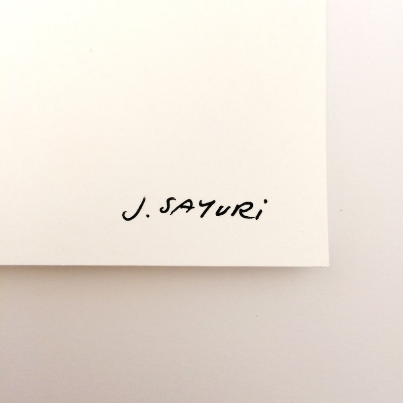 May include: A section of cream-coloured paper with the handwritten signature "J. SAYURI" in black ink. The paper is clean and the signature is in a simple, elegant script.