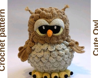 Puede incluir: Un juguete de búho de crochet hecho con hilo marrón y beige. El búho tiene grandes ojos negros, un pico naranja y patas amarillas.