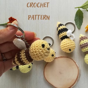May include: Four crocheted bee keychains with black and brown stripes, yellow bodies, and white wings. The keychains are attached to silver key rings. The words "CROCHET PATTERN" are written in black letters on a white background.