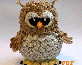 May include: Crocheted owl amigurumi toy with brown and beige yarn, large black eyes, and a small orange beak. The owl has a textured, scaly appearance and is standing on four yellow feet with black claws. The text "PDF pattern" is visible in the lower right corner of the image.
