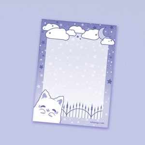 May include: A notepad with a whimsical design featuring a white cat, clouds, stars, and a crescent moon against a purple background. The notepad has a decorative border with a fence design and the text "nkusagi.com".