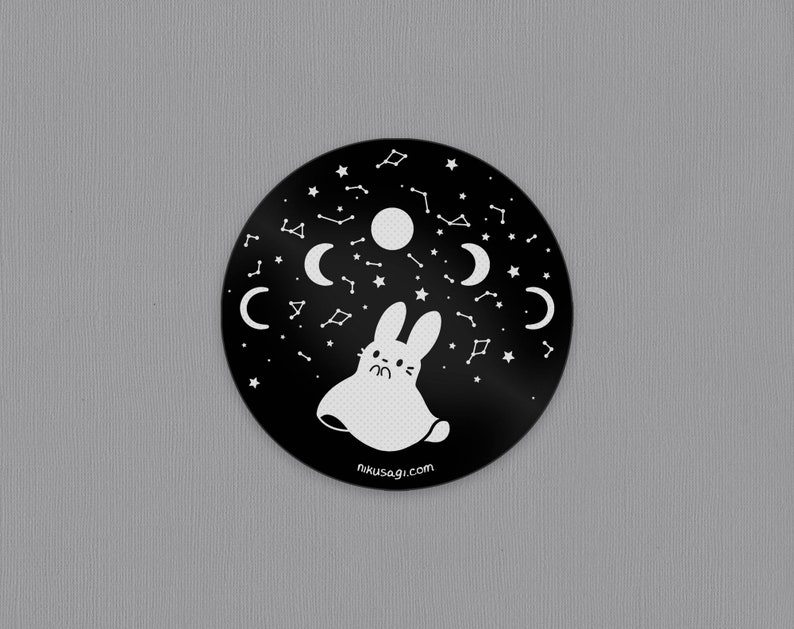 May include: Black and white sticker with a ghost bunny surrounded by stars, moons, and constellations. The sticker has the text "nikusagi.com" at the bottom.