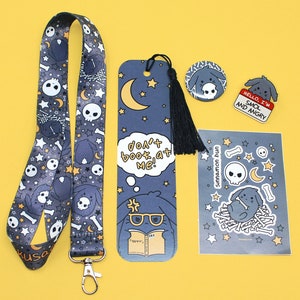 May include: A collection of accessories featuring a cartoon dog design. Includes a lanyard, bookmark, pin, sticker sheet, and a pin with the text "HELLO, I'M SMOL AND ANGRY". The items are primarily dark blue with white, yellow, and black accents.