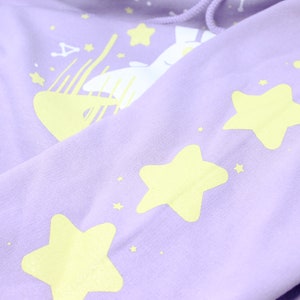 May include: A lavender hoodie with a white bunny and yellow stars printed on it.