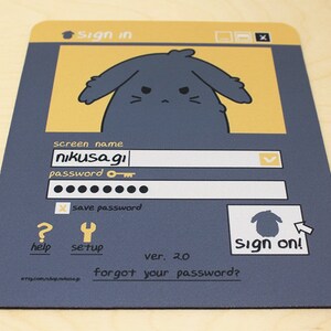 May include: A rectangular mousepad with a cartoon login screen design. The design features a sad-faced bunny character, a screen name field with "nikusagi", and a password field. The mousepad is primarily navy blue and yellow.