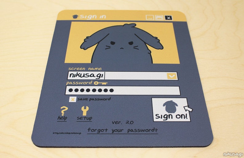 May include: A rectangular mousepad with a cartoon login screen design. The design features a sad-faced bunny character, a screen name field with "nikusagi", and a password field. The mousepad is primarily navy blue and yellow.