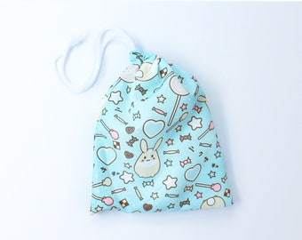 May include: A light blue drawstring bag with a white drawstring. The bag is covered in a pattern of stars, hearts, candy, and a bunny rabbit.