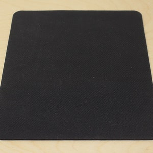 May include: A black rectangular mouse mat with rounded corners. The surface has a textured pattern. The mat is designed for use with a computer mouse, providing a smooth tracking surface.