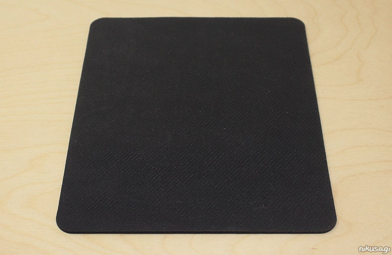 May include: A black rectangular mouse mat with rounded corners. The surface has a textured pattern. The mat is designed for use with a computer mouse, providing a smooth tracking surface.