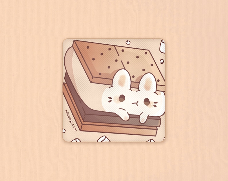 May include: A white bunny peeking out from a chocolate and graham cracker s'more with marshmallows. The s'more is surrounded by white sprinkles on a beige background. The text "nikusagi.com" is printed on the bottom left corner.