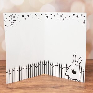 Inside of the card features a cute illustration of the ghost rabbit carrying a black heart and a starry sky.