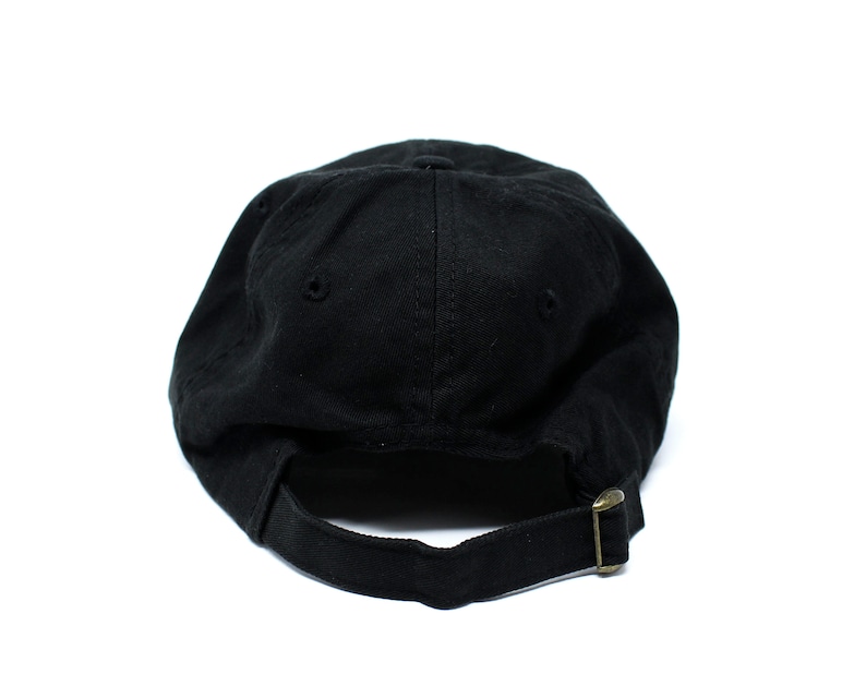 May include: A black baseball cap with a curved brim, viewed from the back. The cap has a fabric strap with a metal buckle for adjustment. The cap is made of a solid, dark fabric.