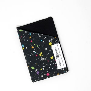Cartera minimalista de lona negra con salpicaduras de pintura