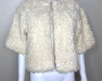 May include: A white faux fur jacket with a short sleeve and a front closure.