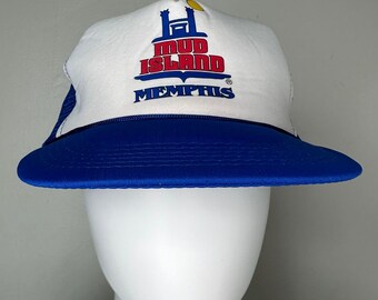 Può includere: Cappellino da camionista bianco e blu con un logo rosso e blu che dice "Mud Island Memphis".