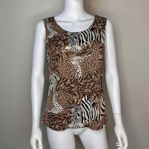 Op de afbeelding: Een top zonder mouwen met een bruine, zwarte en witte dierenprint met zebra's, luipaarden en bladeren.