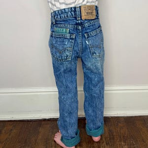 Op de afbeelding: Een blauwe acid wash jeans met een bruin leren Levi's-patch op de achterkant. De jeans heeft een gezoomde zoom en is gemaakt van denim.