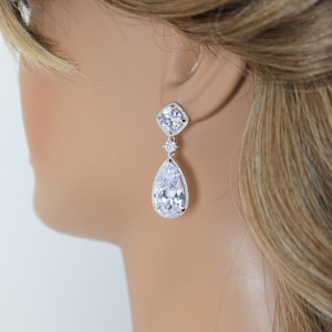 Peut inclure: Une paire de boucles d'oreilles en argent en forme de larme avec des pierres en zircone cubique transparentes. Les boucles d'oreilles présentent une pierre en forme de larme plus grande avec une pierre carrée plus petite au-dessus.