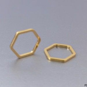 May include: Two gold hexagonal rings on a gray background. The rings are simple and modern in design.
