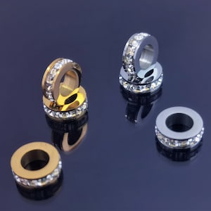 Puede incluir: Cuatro anillos de metal con adornos de cristal transparente. Dos anillos son dorados y dos son plateados.