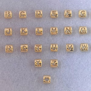 May include: Gold-colored alphabet letter beads with a heart charm. Each bead features a different letter of the alphabet, from A to Z.
