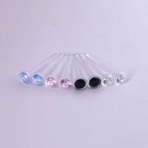 May include: Eight clear glass sticks with different colored gemstone tops. The colors are light blue, dark blue, pink, pink, black, black, clear, and clear.